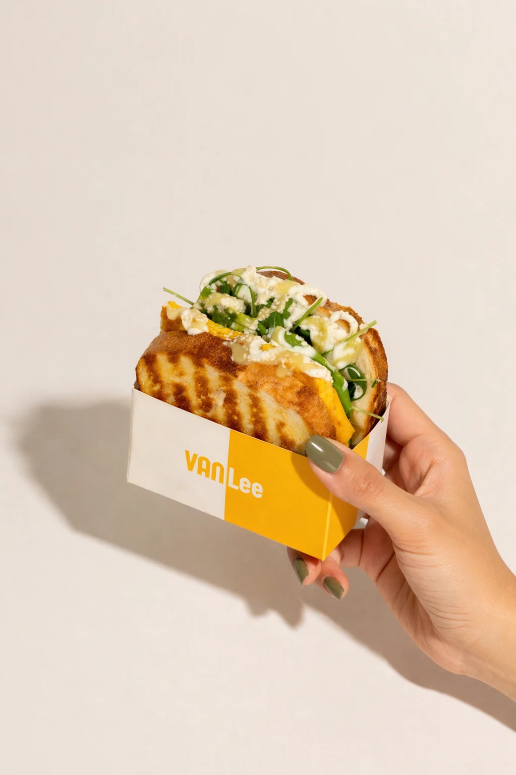 Hand hält ein Eggdrop Sandwich in VANLee-Box